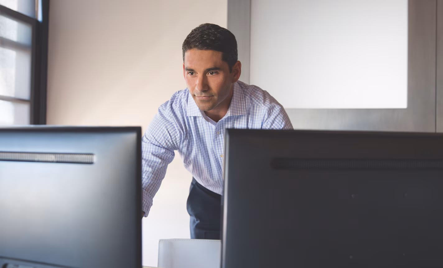 An investor stands near his computer